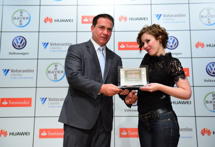 Do Mega Curioso, a analista de conteúdo sênior, Maria Luciana Rincón, recebe o troféu das mãos de Paulo Pereira, Diretor de Comunicação Corporativa da Bayer no Brasil