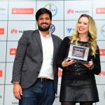A autora e fundadora do Organize Sem Frescuras, Rafaela Oliveira, recebe o seu troféu de Vinícius Fiori, Gerente Sênior de Relações Públicas da Huawei