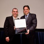 Márcio Cardia, publisher da revista Negócios da Comunicação, entrega placa de homenagem para Valdesir Galvan, CEO da AACD
