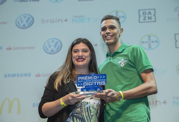 Elisabete Lima, gerente de comunicação e RP do DAZN, entrega o prêmio de "Esportes" para Eurys Oliveira, do Você Sabia? Futebol